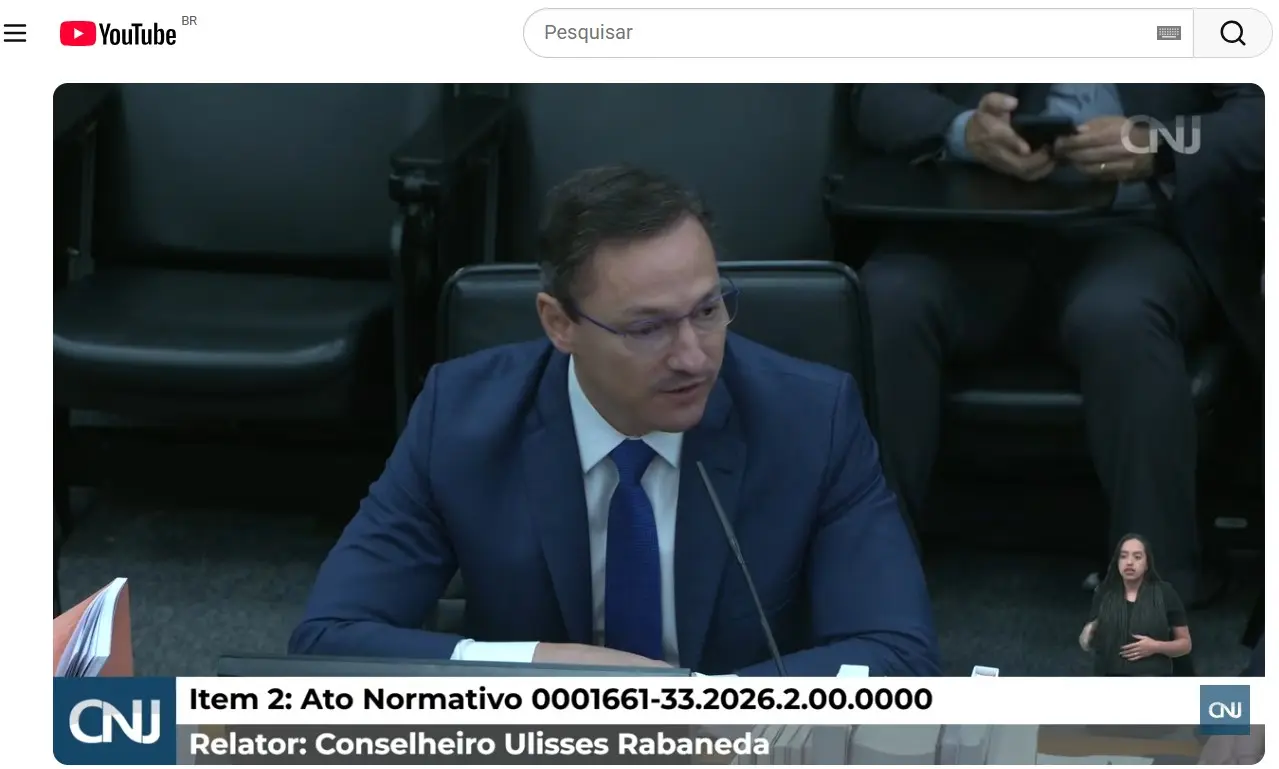 Print de tela. Mostra o conselheiro do CNJ, Ulisses Rabaneda, durante sessão plenária. Ele usa terno azul e está sentado à mesa de julgamentos. Na tela aparecem o número do ato normativo analisado e a identificação do relator.