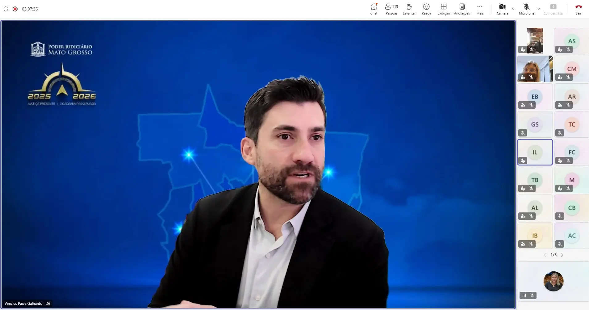 Captura de tela da capacitação virtual. Em destaque, o juiz Vinicius Paiva Galhardo, homem de pele clara, cabelos curtos escuros e barba aparada, vestindo blazer preto e camisa branca. Ao fundo, há um painel virtual azul com a identidade visual do Poder Judiciário de Mato Grosso. À direita da tela a