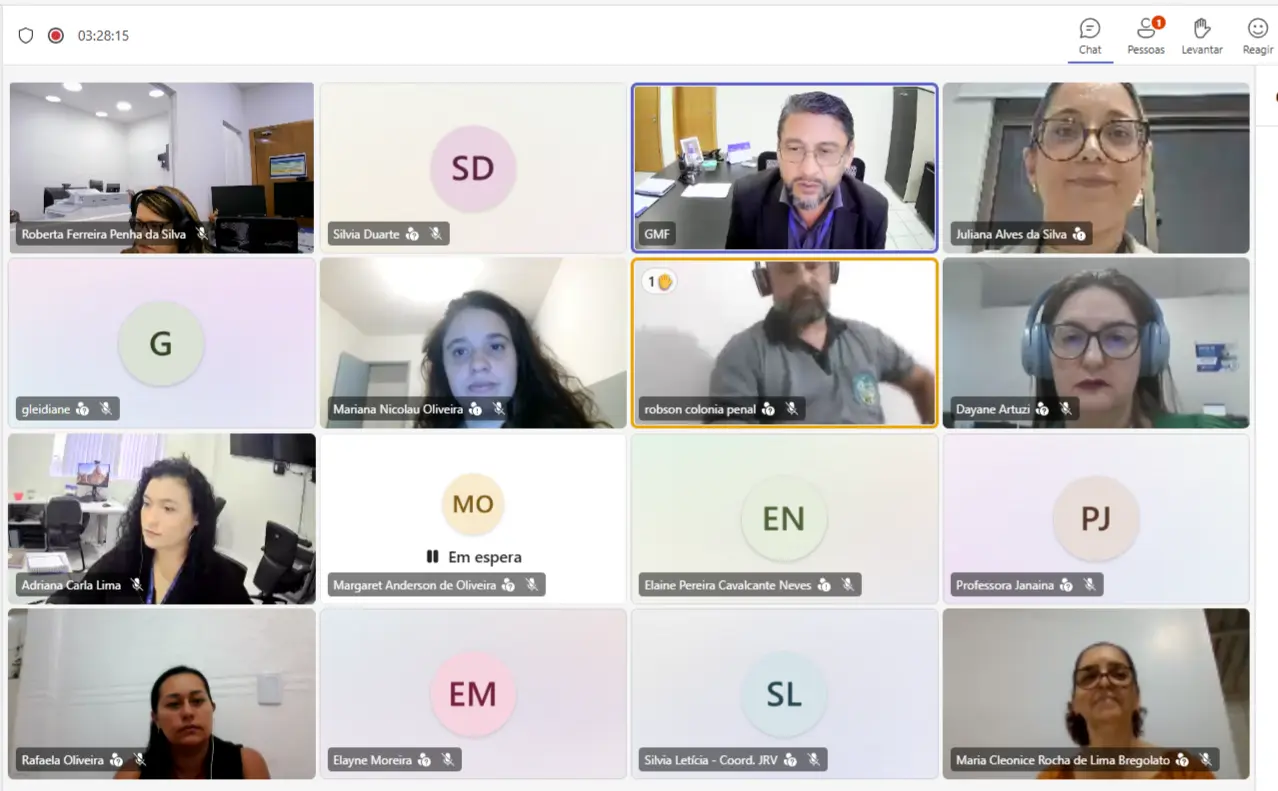 Captura de tela de uma reunião virtual com várias participantes em videoconferência. No centro, um homem de barba e óculos aparece em destaque falando durante o encontro online.
